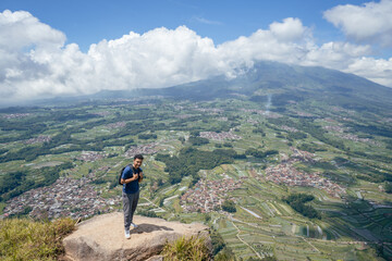 Young man Indonesian hiking mountain through the forest and foot path. The photo is suitable to use for adventure content media, nature poster and forest background.