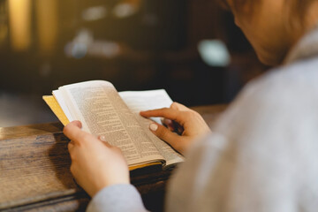Christian woman reading bible in an ancient Catholic temple. Reading the Holy Bible in temple. Concept for faith, spirituality and religion. Peace, hope, dreams concept