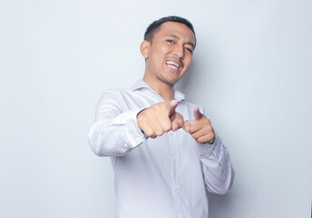 Portrait of smiling young handsome Asian man pointing fingers in empty space