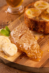 banana honey cake with wild honeycomb and banana slices on rustic wooden table in macro close-up from above