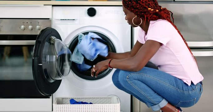 Young Woman Putting Clothes Into Washing Machine