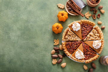 Traditional Thanksgiving pies cut into slices with pumpkin, pecan and crumble - obrazy, fototapety, plakaty