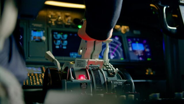 Close-up of a pilot's hand pressing the throttle in the cockpit of a jet plane reducing engine power