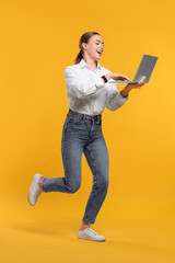 Happy woman with laptop running on orange background