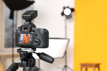 Tripod with camera, bar stool and professional lighting equipment in modern photo studio, focus on screen. Space for text © New Africa