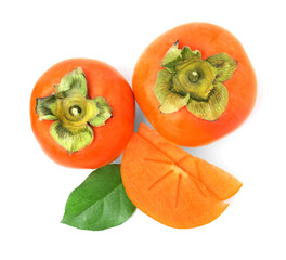 Whole and cut delicious ripe juicy persimmons with green leaf on white background, top view