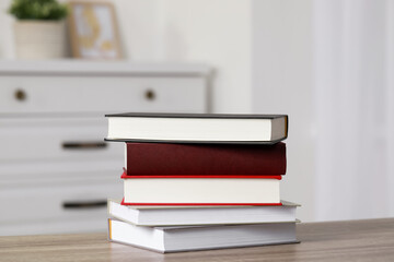 Stack of hardcover books on wooden table indoors