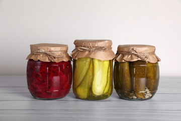Jars with different preserved vegetables on wooden table