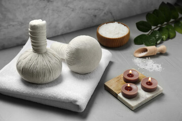 Spa composition with herbal bags and burning candles on light grey table