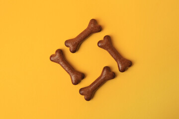 Bone shaped dog cookies on orange background, flat lay