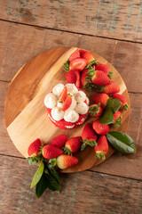 strawberry cake with white chocolate cream and strawberries around on rustic table top view