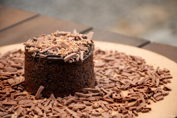 chocolate cake with chocolate shavings and chocolate cream on rustic bistro table in close-up blurred background outside macro