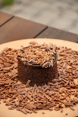 chocolate cake with chocolate shavings and chocolate cream on rustic bistro table in close-up blurred background outside macro portrait