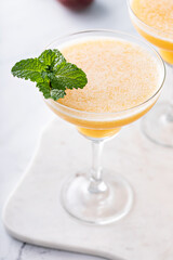 Frozen peach margaritas in three glasses with mint