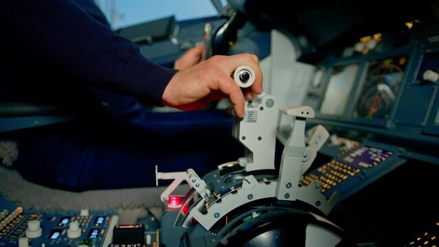 Close-up of a pilot's hand pressing the throttle in the cockpit of a jet plane reducing engine power