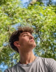 Naklejka na ściany i meble Side view of a young man who is looking up over nature background