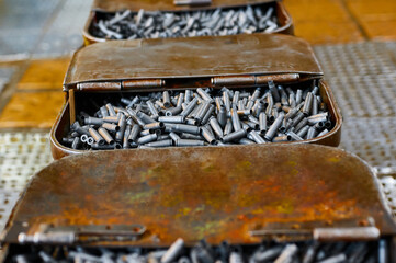Metal containers full of bullet casings on table at plant