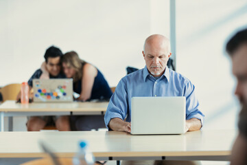 Mature man with laptop in library