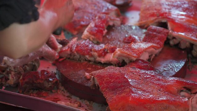 Chefs are cutting up charcoal-grilled roast pigs at a Chinese food stall