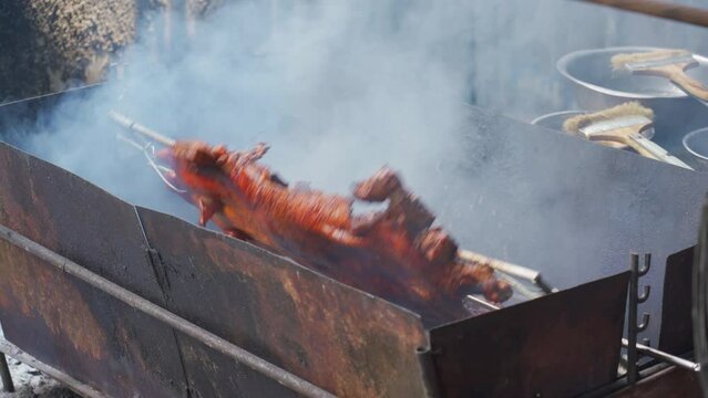 A roaster in China roasts a whole crispy-skinned pork over charcoal fire