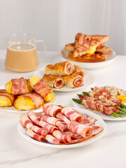 Bacon in a plate, bacon pork rolls in various recipes, on a white kitchen tabletop, indoor scene