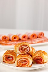 Bacon in a plate, bacon pork rolls in various recipes, on a white kitchen tabletop, indoor scene