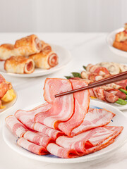 Bacon in a plate, bacon pork rolls in various recipes, on a white kitchen tabletop, indoor scene