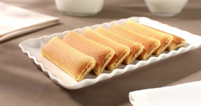 cookies with milk on the table. strudel with fruit filling on a white plate. pastries on a brown background. sweet treat on a sunny day.