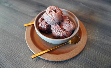 Gelato. Italian Gelato. Premium chocolate gelato in ceramic bowl with golden spoon and dish on wooden table