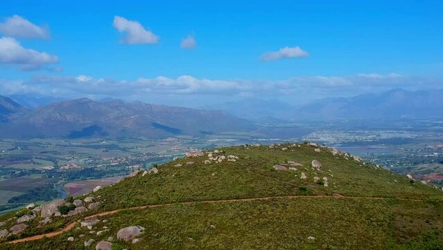 Arial drone view of hill top with mountains in distance and houses in valley below, Paarl South Africa