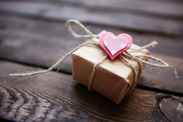Image of valentine giftbox with small pink heart on wooden background