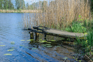 Spalony drewniany pomost położony nad wodą  w jeziorze służący do połowu ryb , palić za sobą mosty - obrazy, fototapety, plakaty