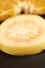 Guava in close-up, with a blur of a fruit bowl.