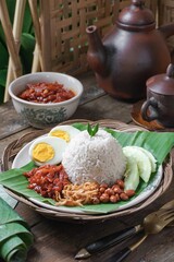 Asian cuisine Nasi Lemak is a rice dish infused with coconut milk. Served with sambal sauce, fried anchovies, fried peanuts, boiled eggs, and fresh cucumber.
