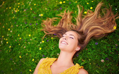 Top view, relax or woman on grass, flowers or freedom with happiness, care or healthy. Female person, natural or happy lady with a smile, carefree or wellness outdoor, nature or spring time with hair