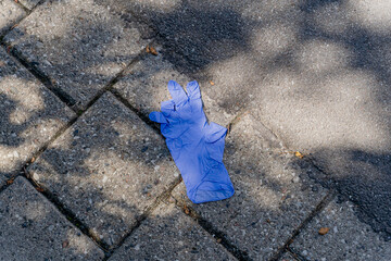 The medical glove lies on the asphalt.