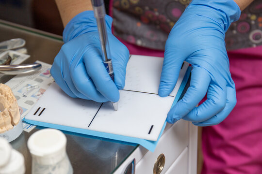 Nurse's hands making holes in the rubberdam