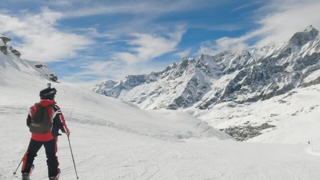Male skier stand and look at mountain range panorama in Cervinia ski resort Italy