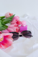 Pink tulips, sunglasses and perfume bottle on white background, women cosmetics set