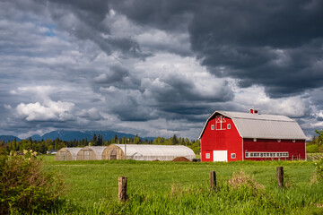 Agriculture Landscape With Old Red Barn and dark clouds. Countryside landscape. Farm, red barn. Rural scenery, farmland
