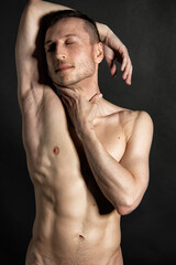 Naklejka premium Young attractive man with an athletic body on a black background.