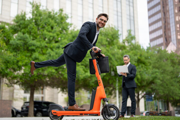 Crazy business, fast and easy. Business man in a suit riding an electric scooter on a business meeting. Happy businessman with scooter outdoor. Funny business man riding an electric scooter.