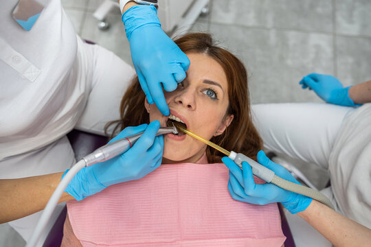 Close-up cropped photo of woman with open mouth holding mirror for dental equipment.