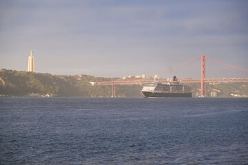 Luxury ocean liner cruiseship cruise ship Victoria or Elizabeth in port of Lisbon, Portugal during Mediterranean cruising with city skyline, Christos statue and suspension bridge