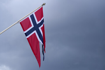 The national flag of Norway waving against cloudy sky. Concept image for Kingdom of Norway.
