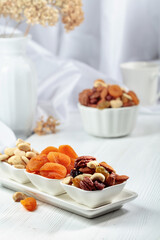 Dried fruits and assorted nuts on a white table.