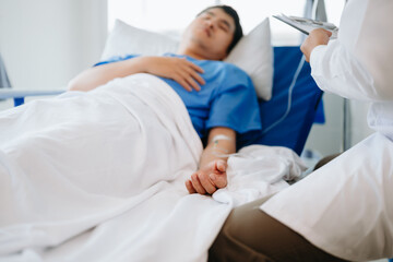 Obraz premium Female doctor holding male patient hand on the bed with receiving saline solution in hospital or clinic..