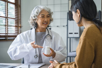 Obraz premium female doctor giving advice to young female patients about medicine Doctor prescribing medicine sitting at a table in a hospital.