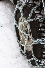 Close up. Winter chains of anti-skid on a motor-car wheel. Safe driving in deep snow in winter road.
