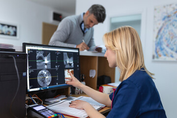 Attentive dentist examining an x-ray on computer in dental clinic